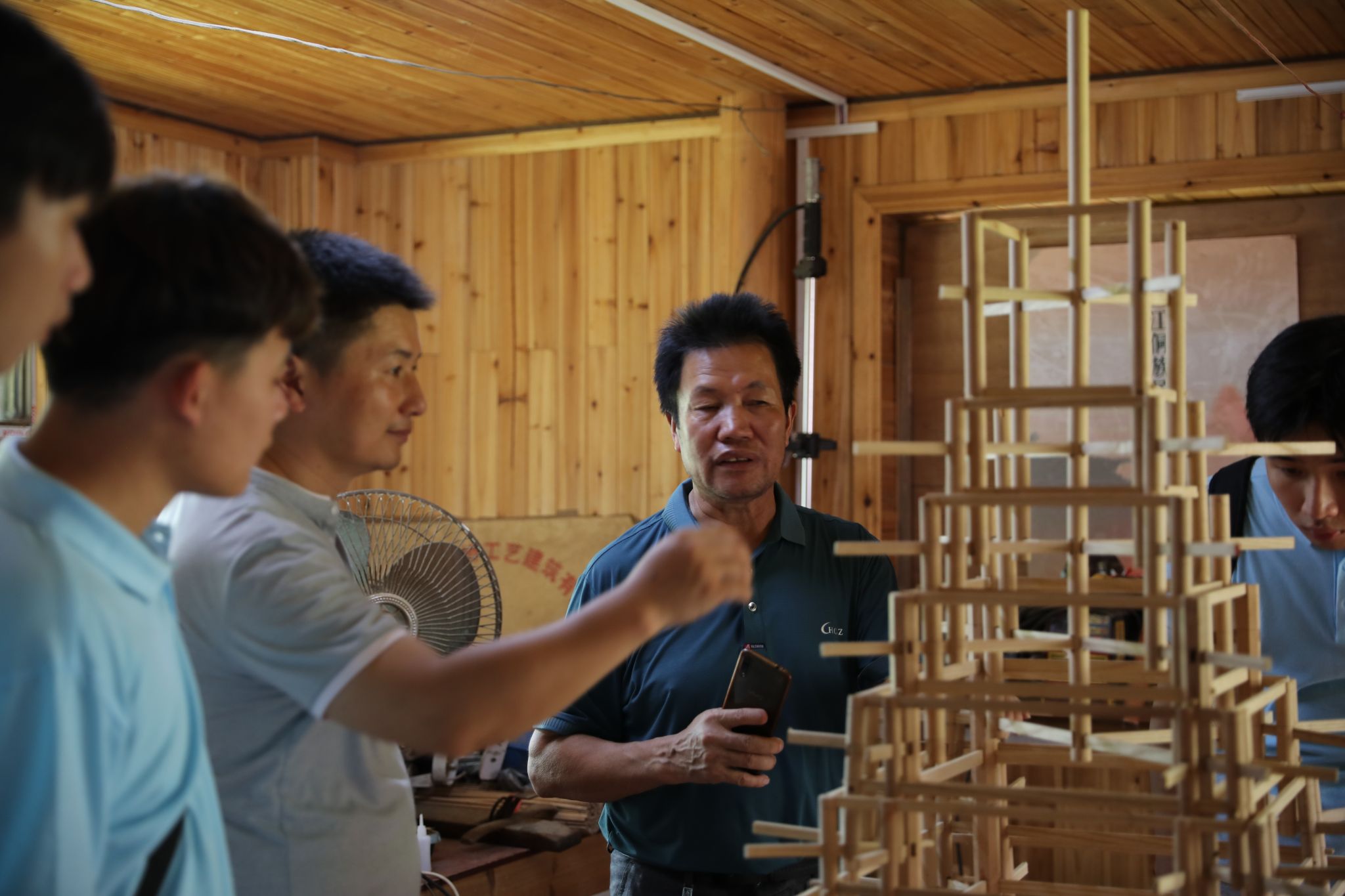楊似玉大師利用鼓樓模型向?qū)嵺`團成員解說鼓樓建筑結(jié)構(gòu)